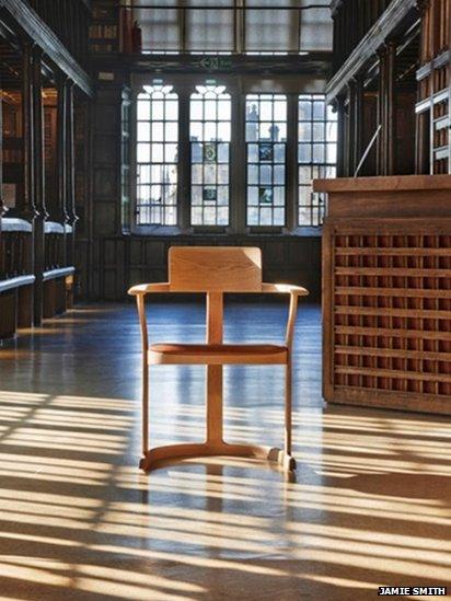 Three-legged oak chair in front of a window