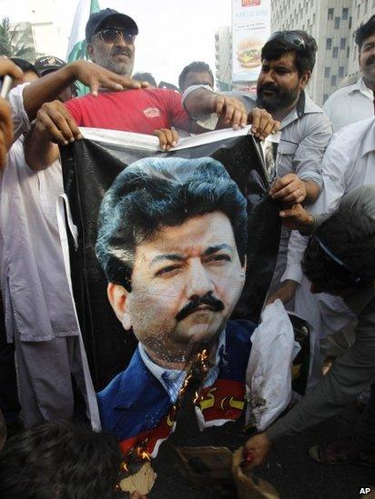 Supporters of the Pakistan army burn a poster of Pakistani anchorperson Hamid Mir at a rally in Karachi, Pakistan (26 April 2014 photo)