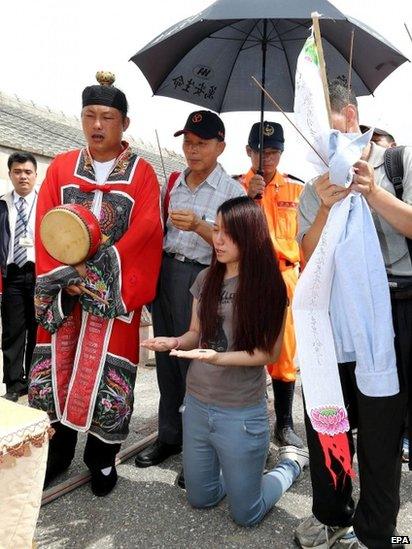 A Taoist priest (L) performs a ritual to appease the souls of the dead for a victim of the TransAsia Airways plane crash on the Penghu Islands in the Taiwan Strait, 24 July 2014.