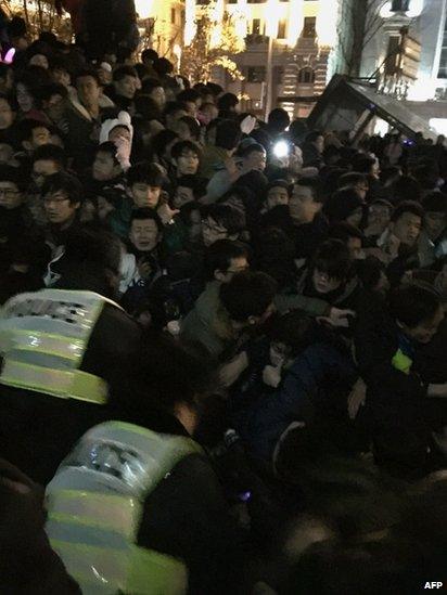 Policemen try to help revellers trapped in a stampede as people gather on Shanghai's historic riverfront to welcome in the new year on 31 December 2014