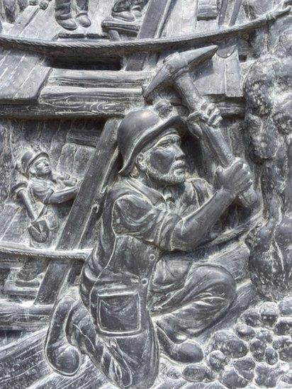 Stone carving of miner statue