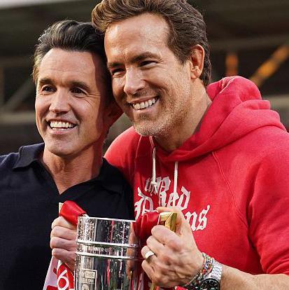 Rob McElhenney and Ryan Reynolds pose with the trophy following Wrexham's promotion to the Championship