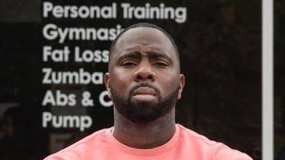 Javeno in front of a window reading Personal Training Gymastics Fat Loss Zumba. He is wearing a salmon jumper