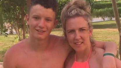 Connor Smith, who is not wearing a shirt, has short brown hair and Tracey Williams has blonde hair in a bunch and is wearing a pink top. They are both smiling. It is summer.