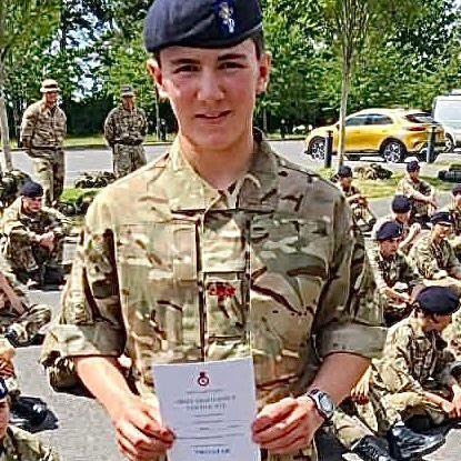 Will is wearing a camouflage uniform and beret of the Army Cadets. He is holding an award certificate.