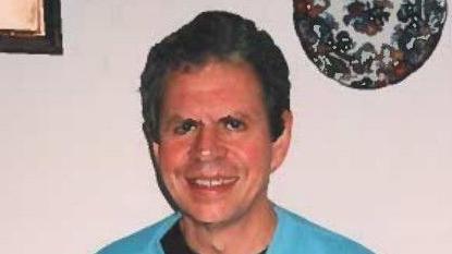 Stephen Ridgeway wearing a blue jumper over a black T-shirt. He has dark hair and is smiling.
