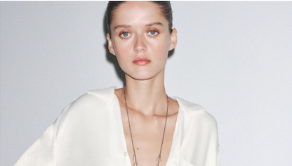 A pale model poses in a white Zara shirt staring at the camera with a blank expression and the low cut design of the top shows her protruding collarbones