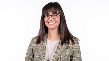 A portrait image of Dr Inga Stewart. She has shoulder length brown hair and is wearing glasses and a patterned blazer.