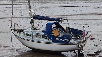 A picture of Guy's boat in the sea. It is a large white boat with a blue sign saying 'Swallow' on the side of it.
