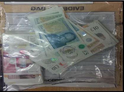 Cash in a sealed evidence bag, various notes including £5, £10 and £50 are seen