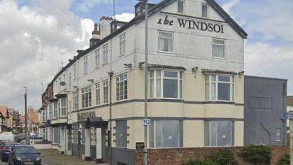 The Windsor is written on the side of the building, which is boarded up on the ground floor.