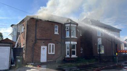 The end-of-terrace with smoke pouring out of a roof space 