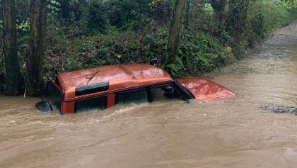 An orange 4x4 vehicle can be seen partly submerged. The water comes half way up the vehicle's windows.