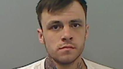 Mugshot of a man with short dark hair and a serious expression.