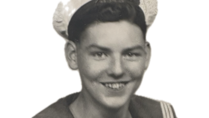 A black and white image of Richard Wood's head and shoulders in his naval uniform, including his white peaked cap.