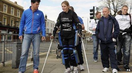 Woman with crutches and body suit walks with 3 other people