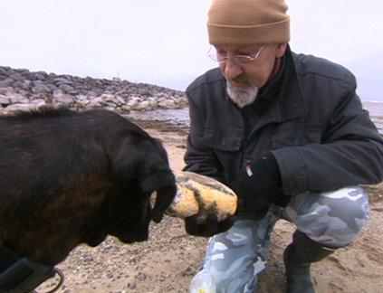 Ken Wilman holding a lump of ambergris while his dog Madge sniffs it.