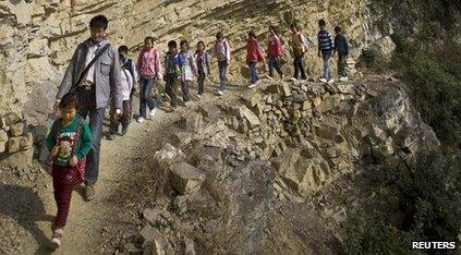 Students walking to school on narrow paths along the side of a mountain in China