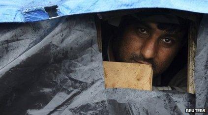 An Afghan migrant looks out the window of his makeshift shelter at the harbour in Calais