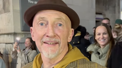 Football manager Ian Holloway wearing a brown trilby and checkered suit jacket over a hoodie.