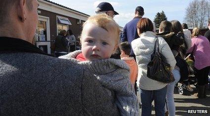 Adults and children queue outside a hospital in Swansea to be vaccinated against measles