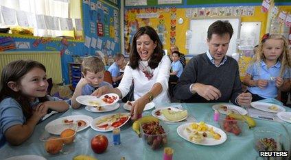 Nick Clegg and his wife sit with children at a school