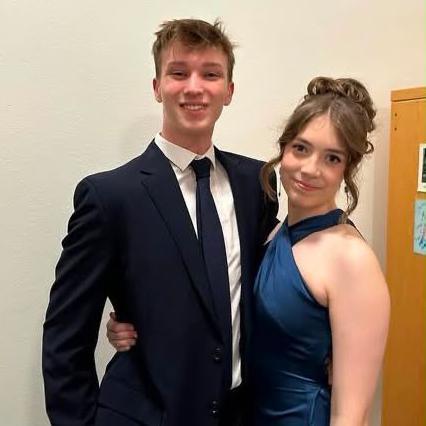 Harrison and his girlfriend are standing in the room, looking at the camera and smiling