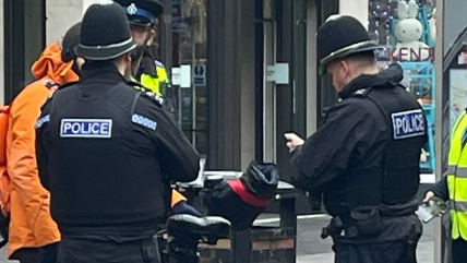 Three police officers talking to a food delivery rider outside the Highcross shopping centre