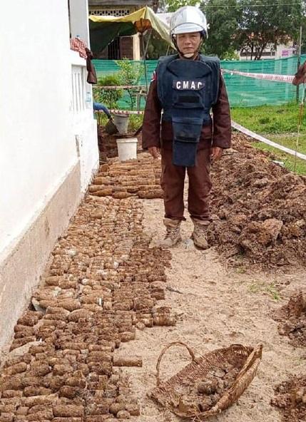 A deminer standing next to thousands of unexploded ordnance left over from Cambodia's civil war, August 13, 2023