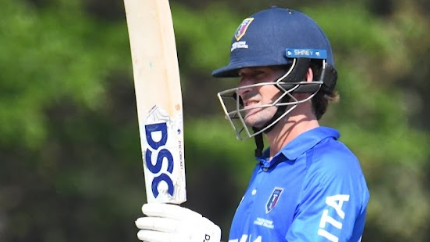 Joe Burns raises his bat to salute making a hundred for Italy
