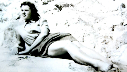 A black and white photo of a women lying on the beach