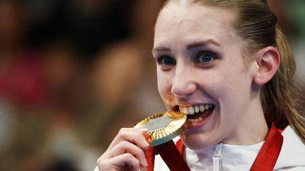 Louise Fiddes bites her gold medal