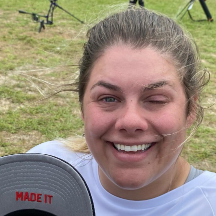 Tracy Otto smiles while holding a cap with the message 'Made it' showing