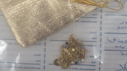 A gold chain and small gold pouch bag are seen in a police evidence bag.