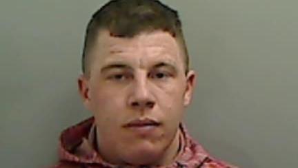 Mugshot of John Grey. He is clean shaven and has short dark hair with shaved sides.