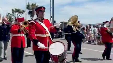 Three men in red uniforms play the drums