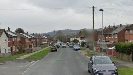 Road running through centre of image flanked by semi detached houses.