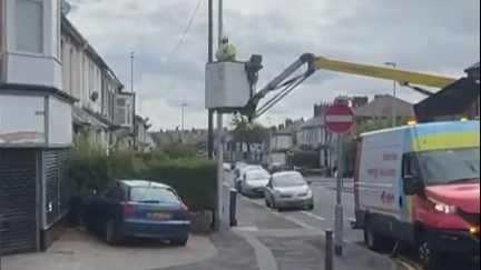 A worker uses a crane to remove a union jack on a street in Blackpool