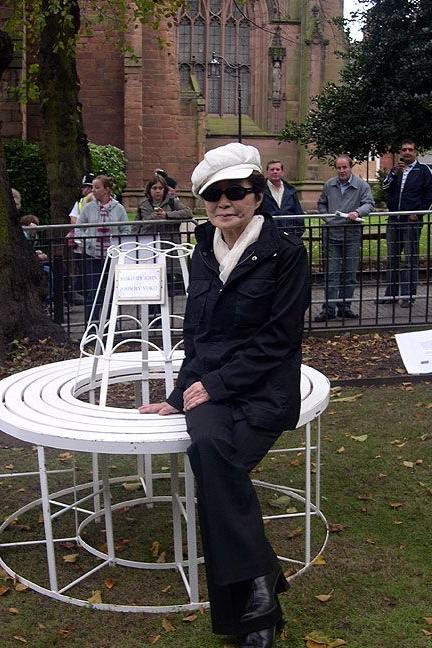 Yoko Ono pictured sitting on a replica of the original bench she and John Lennon had brought to the city in 1968