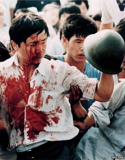 A blood-covered protester holds a soldier's helmet after violent clashes in Tiananmen Square on 4 June 1989