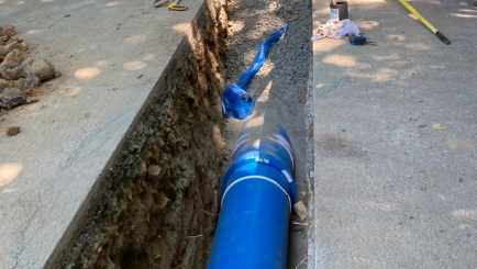 A blue pip in the ground. The concrete is grey. 