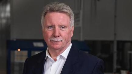 Evtec's chairman David Roberts wearing a suit jacket and opened collared shirt. He has short grey hair and a moustache 