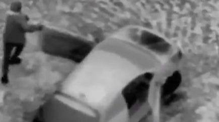 Still from police helicopter video of men leaving the car that had been followed by South Yorkshire Police. Black and white thermal image of a man (left) and a car (right).