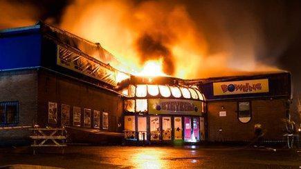 Night-time photograph of a fire bursting from a bowling alley building