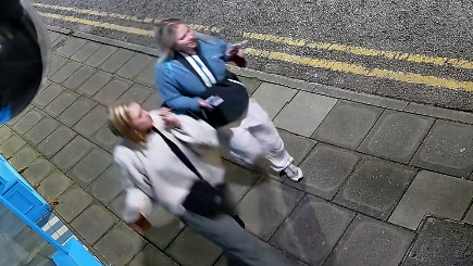 Two women walking down a pavement