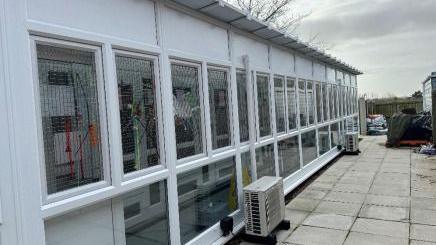 An exterior view of the cattery, which is white and has a series of windows giving a view onto a patio area