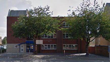 Three-storey brick office building with trees in front