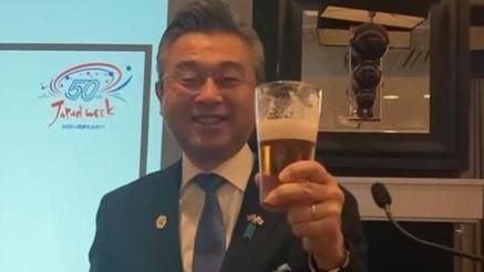 The ambassador is smiling as he holds a pint of beer