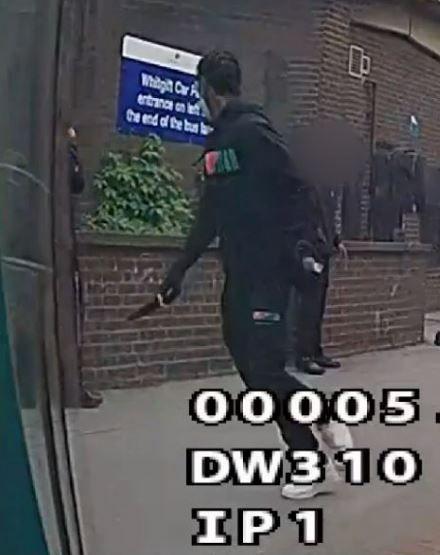 A CCTV image of a young man in black tracksuit top and bottoms and black gloves with a knife in his right hand. His face is turned away from the camera. 