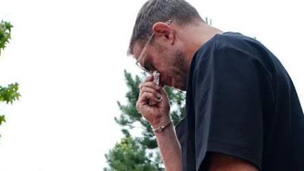 Jordan Henderson, wearing a black T-shirt and sunglasses, is tearful as he looks at tributes to Diogo Jota around Anfield